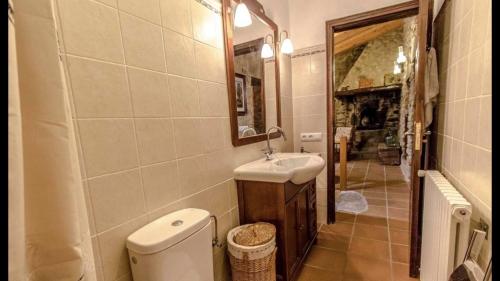 bagno con servizi igienici, lavandino e specchio di CAL CARRETER a Foixá