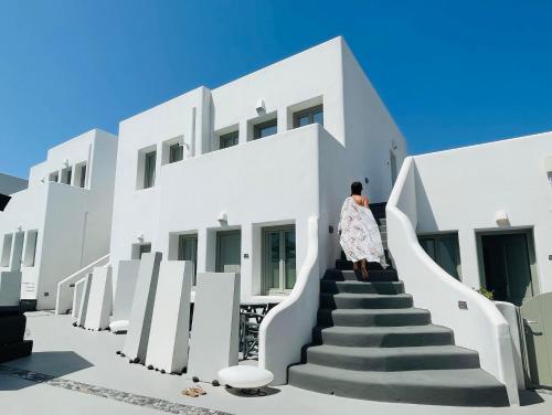 a woman walking up the stairs of a white building at Kallos Imar Boutique Hotel in Mesaria