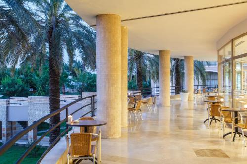 a lobby with tables and chairs and palm trees at Lucida Beach - All Inclusive in Kemer
