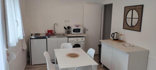uma pequena cozinha com uma mesa branca e um lavatório em Ici c'est le Marais Poitevin em Ferrières