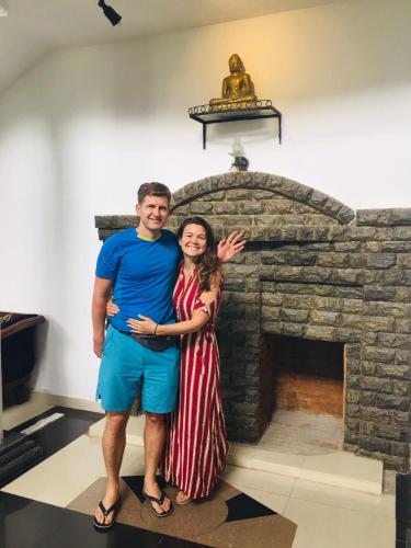 a man and a woman standing in front of a stone fireplace at Ceylon Breeze in Kandy