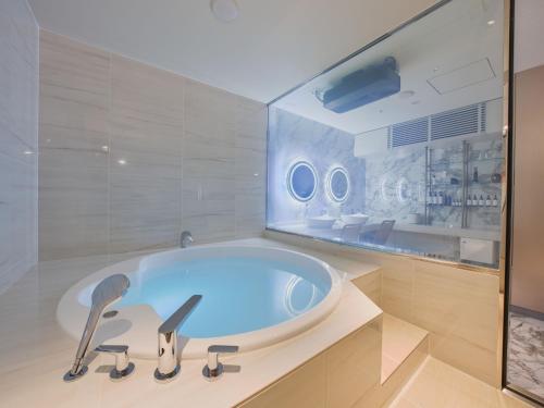 Villa Fontaine Grand Osaka Umeda في أوساكا: حوض استحمام في الحمام بجدار زجاجي