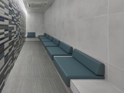 a waiting room with blue benches in a building at Villa Fontaine Grand Osaka Umeda in Osaka