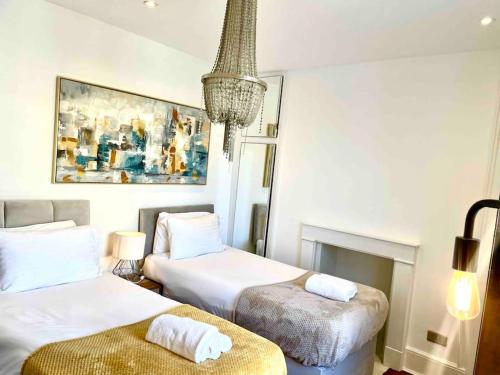 劍橋的住宿－EMMANUEL HOUSE LOVELY 1 - BEDROOM APT IN HISTORICAL BUILDING CENTRAL CAMBRIDGE，酒店客房设有两张床和吊灯。