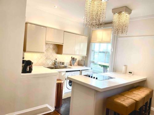 劍橋的住宿－EMMANUEL HOUSE LOVELY 1 - BEDROOM APT IN HISTORICAL BUILDING CENTRAL CAMBRIDGE，厨房配有白色橱柜、水槽和柜台。
