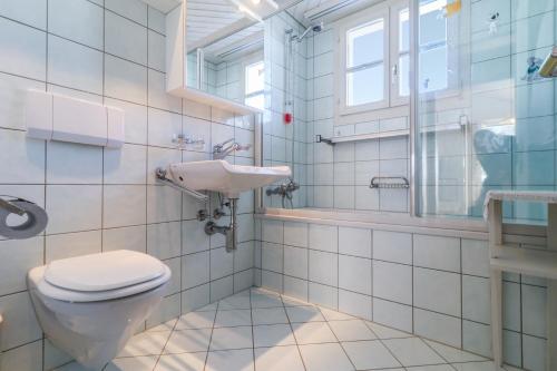 a bathroom with a toilet and a sink at The Swiss Paradise 2 Apartment with Garden, Whirlpool, and Mountain Panorama in Wirzweli