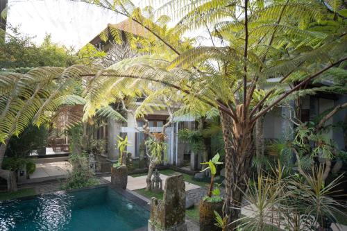 a swimming pool in a garden with a palm tree at Prabhu Ubud Villa in Ubud