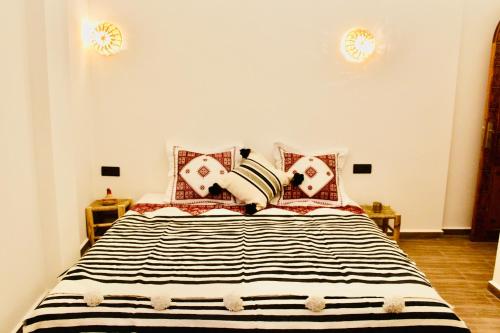 a bedroom with a bed with black and white pillows at TRAVEL SURF NATURE in Tamraght Ouzdar