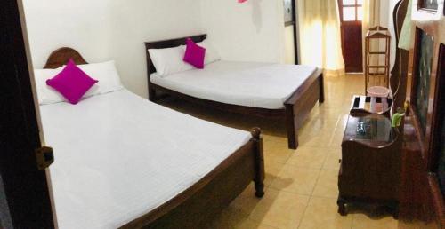 two beds with pink pillows in a room at Sunila Family Rest Anuradhapura in Anuradhapura