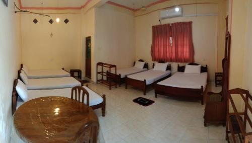a room with four beds and a wooden table at Sunila Family Rest Anuradhapura in Anuradhapura