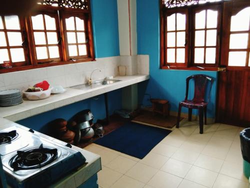 a kitchen with blue walls and a stove top oven at Sunila Family Rest Anuradhapura in Anuradhapura