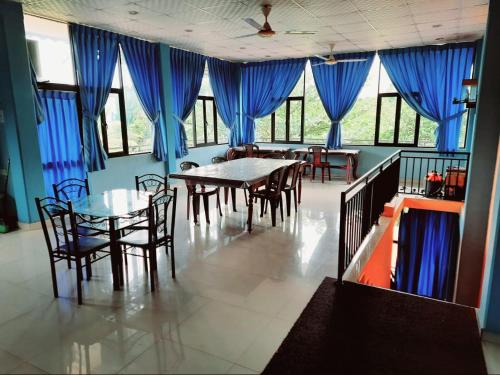 a dining room with blue curtains and tables and chairs at Sunila Family Rest Anuradhapura in Anuradhapura