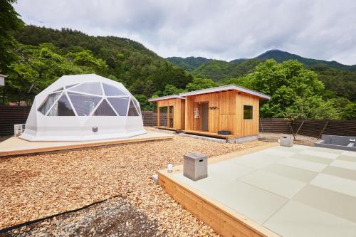 a tent and a cabin with mountains in the background at dots by Dot Glamping Suite 001 in Fujikawaguchiko