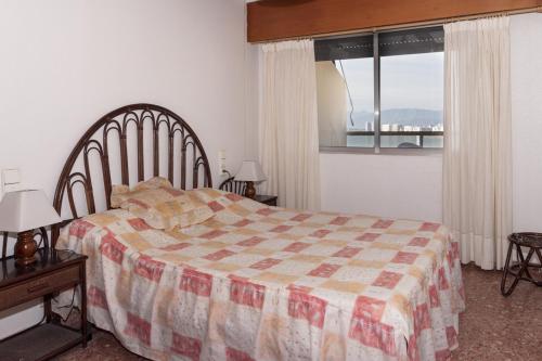 1 dormitorio con 1 cama con manta a cuadros y ventana en Florazar 2, Iv-14-C, en Cullera