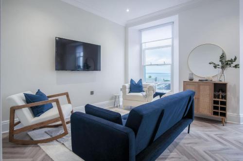 a living room with a blue couch and a mirror at No 4 Croft House - Luxury 2 Bed Apartment - Tenby in Tenby