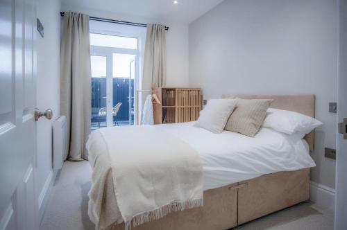 No 4 Croft House - Luxury 2 Bed Apartment - Tenby في تينبي: غرفة نوم بسرير كبير عليها شراشف ووسائد بيضاء