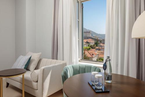 a living room with a table and a couch and a window at Hilton Imperial Dubrovnik in Dubrovnik