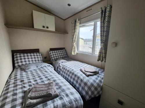 two beds in a small room with a window at D&A's Short Breaks - St Margarets Bay, Dover in St Margarets at Cliff