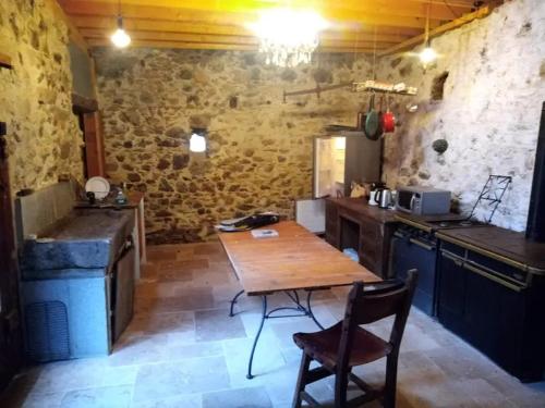 une cuisine avec une table en bois et une table et des chaises dans l'établissement La Maison de Port à la Duc, à Pléboulle