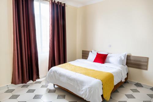 um quarto com uma cama grande e uma almofada vermelha em Mang City Hotel em Nairobi