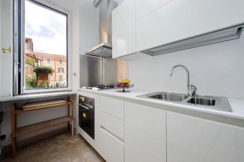 a kitchen with white cabinets and a sink and a window at On The Steps in Rome
