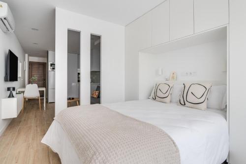 1 dormitorio blanco con 1 cama blanca grande y paredes blancas en Home2Book Stylish Apartment Playa del Inglés, en Maspalomas