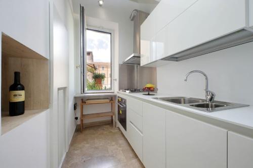 a white kitchen with a sink and a window at On The Steps in Rome
