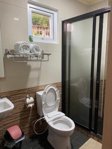 a bathroom with a shower and a toilet and a sink at MinshukuKCS Hotel and Restaurant in Puerto Galera