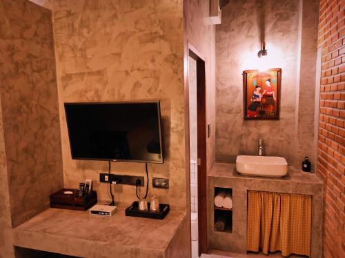 a bathroom with a television and a sink in a room at Greyhouse Homestay 