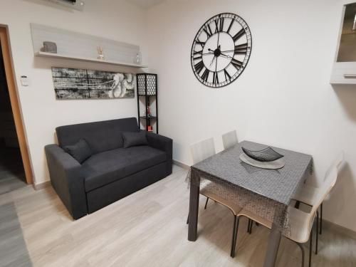sala de estar con sofá, mesa y reloj en Coquet 2 pièces entièrement rénové et climatisé, en Cannes