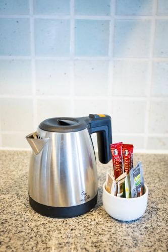 a tea kettle sitting on a counter next to a bowl of butter at Chatrium Sathon Bangkok in Bangkok