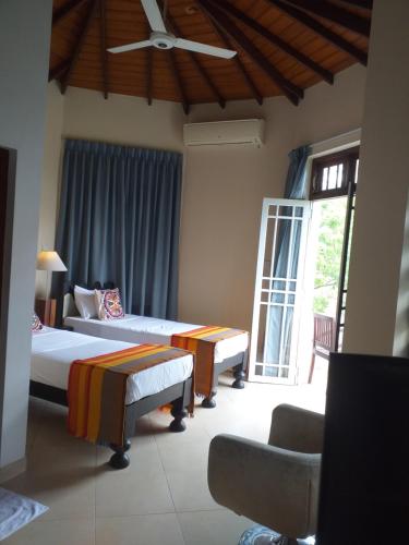 a hotel room with three beds and a window at Crown hills kandy in Kandy