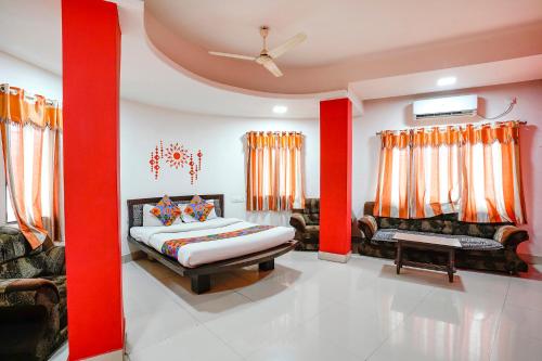 a bedroom with red walls and a bed and a couch at FabExpress Sai Lodging in Nashik
