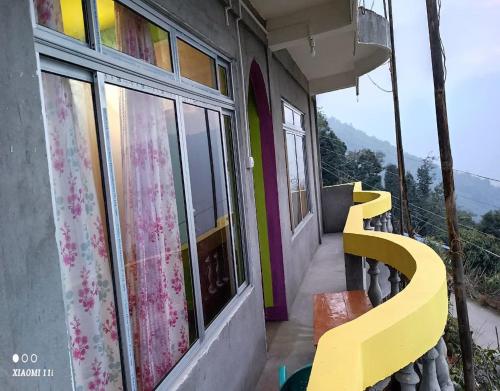 um banco amarelo sentado fora de uma casa com uma janela em Rinchen Ghising Homestay by StayApart em Ghum
