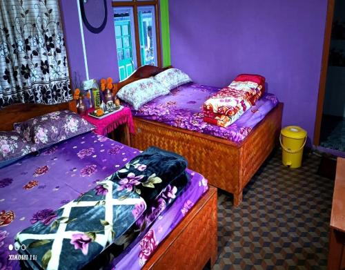 duas camas num quarto com paredes roxas em Rinchen Ghising Homestay by StayApart em Ghum