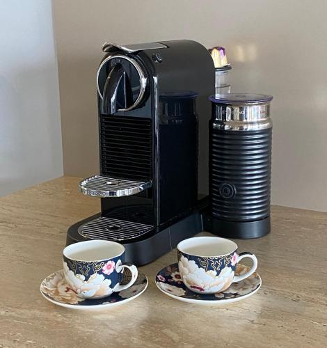 two cups on plates next to a coffee maker at Saltair Luxury Accommodation - Adults Only in Albany