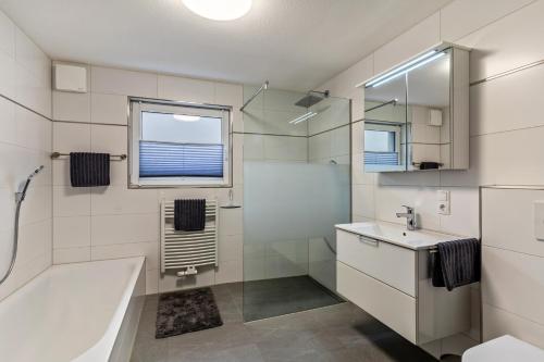 ein Bad mit einer Badewanne, einem Waschbecken und einem Fenster in der Unterkunft Casa di Michelle in Ringsheim