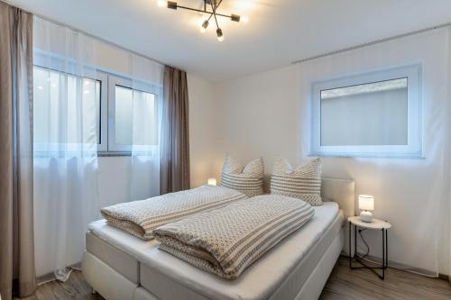 ein weißes Schlafzimmer mit einem Bett mit Kissen und einem Fenster in der Unterkunft Casa di Michelle in Ringsheim