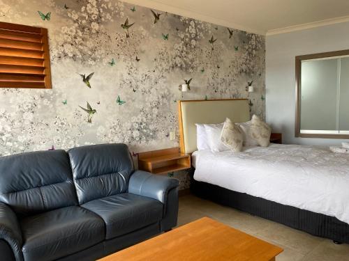 アルバニーにあるSaltair Luxury Accommodation - Adults Onlyのベッドとソファ付きのホテルルーム