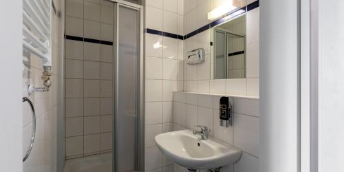 a white bathroom with a sink and a shower at a&o Stuttgart City in Stuttgart