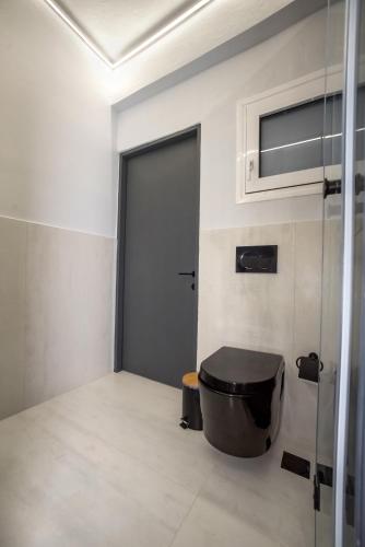 a bathroom with a black toilet and a door at V.L.A Apartments by the sea in Vari