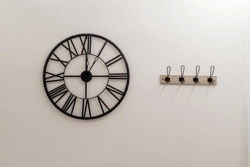 a black and white clock on a wall with two hooks at V.L.A Apartments by the sea in Vari