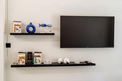 a flat screen tv on a wall with a shelf at V.L.A Apartments by the sea in Vari