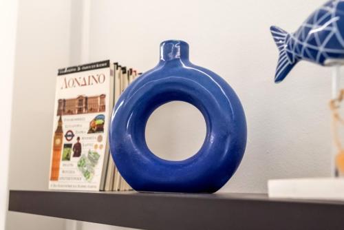a blue vase sitting on a shelf next to books at V.L.A Apartments by the sea in Vari