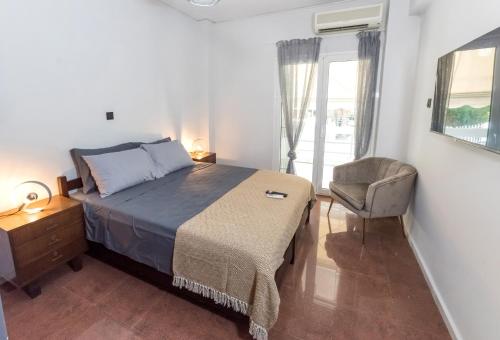 a bedroom with a bed and a chair and a window at V.L.A Apartments by the sea in Vari