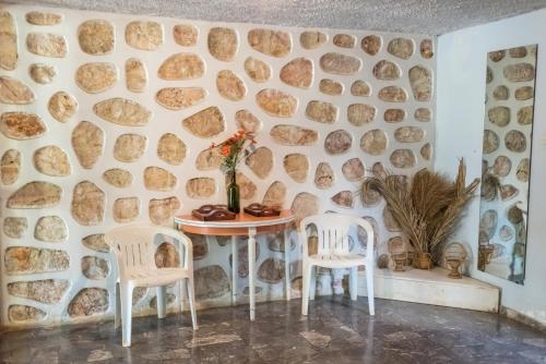 a table and two chairs in a room with a stone wall at V.L.A Apartments by the sea in Vari