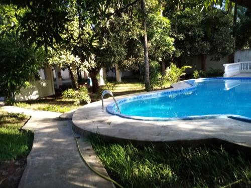 a swimming pool in a yard with trees at LeoMar 2 Diani Beach Ferienhaus mit grossen tropischen Garten und Pool in Ukunda