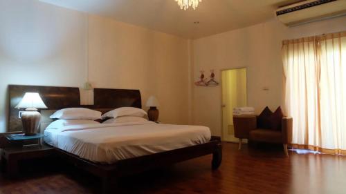 a bedroom with a large bed and a chair at โรงแรมไทยงามพาเลซ (Thai Ngam Palace Hotel) in Kaeng Khlo