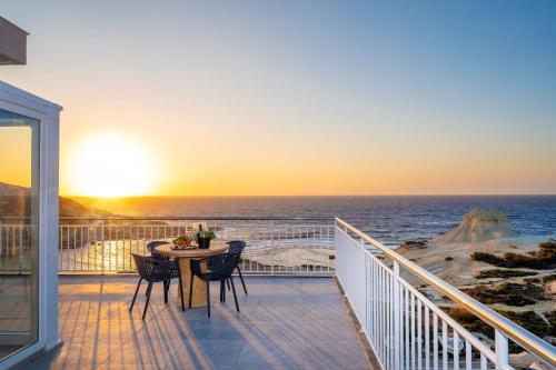 a balcony with a table and chairs and the ocean at Salini Suites in Żebbuġ