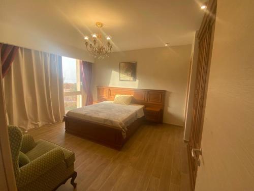 a bedroom with a bed and a chair and a chandelier at Il monte galala in Ain Sokhna